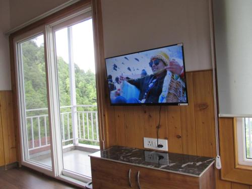 una TV a schermo piatto su un muro accanto a una finestra di The Great Escape Homestay, Gagar, Nainital a Rāmgarh