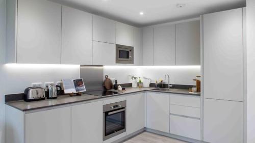 a kitchen with white cabinets and a stove top oven at Stylish Furnished Room In Barking Centre in Barking