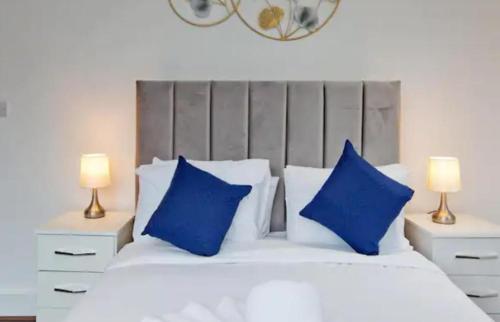 una camera da letto con un letto con cuscini blu e 2 lampade di Stylish Furnished Room In Barking Centre a Barking