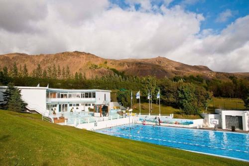 un complejo con una gran piscina junto a una montaña en Riverfront Paradise Villa, en Hveragerði