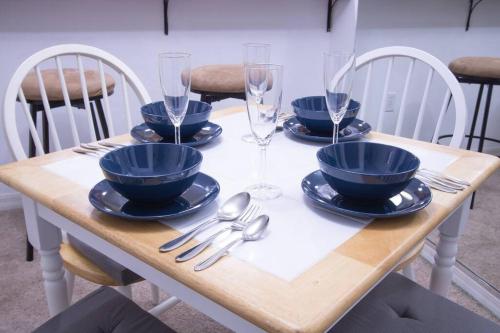 a wooden table with blue bowls and plates and wine glasses at Modern Boho Condo with a Royal Touch -KING BED in Gainesville
