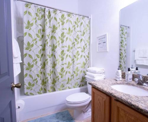 a bathroom with a shower curtain with a toilet and a sink at Modern Boho Condo with a Royal Touch -KING BED in Gainesville