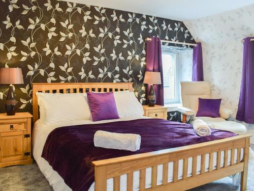 ein Schlafzimmer mit einem großen Bett mit violetter Bettwäsche in der Unterkunft Tayberry Cottage in Aberfeldy