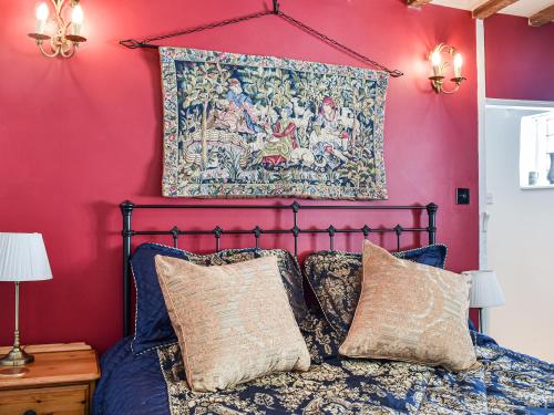 um quarto com paredes cor-de-rosa e uma cama com almofadas em Canons Hall Cottage em Wingham