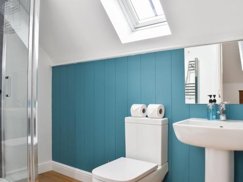 baño con paredes azules, aseo y lavamanos en Roe Cottage - Uk33490 en Hadleigh