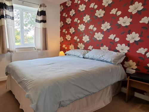 a bedroom with a bed with a red wall at Widgeon Cottage - Uk33873 in Cote