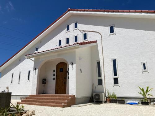 a white church with a wooden door and stairs at ZARATAN in Motobu