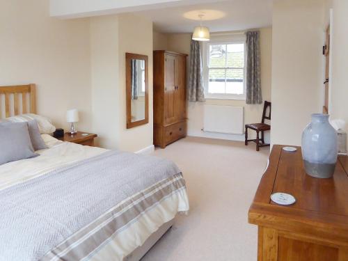 um quarto com uma cama grande e uma mesa de madeira em Tuppence Cottage em Dulverton