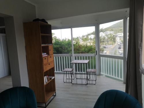a room with a balcony with a table and stools at Moana Beach Apartment in Noumea