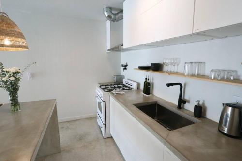 a white kitchen with a sink and a stove at ConCrete Suite 5 Min Walk to Shands UF in Gainesville