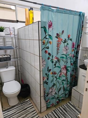a bathroom with a shower curtain with a toilet at VHouse 2 in Bora Bora