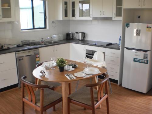 a kitchen with a wooden table and a white refrigerator at RIVER DOWNS COTTAGE in Clarence Town