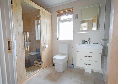 uma casa de banho com um WC, um lavatório e um chuveiro em Athelington Hall Farm Lodges em Horham