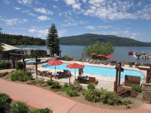 a pool with tables and umbrellas next to a lake at Lodge at Whitefish Lake in Whitefish