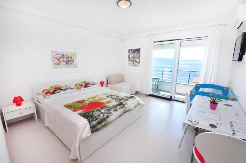 a white bedroom with a bed and a view of the ocean at Apartments Zorka Leko in Omiš