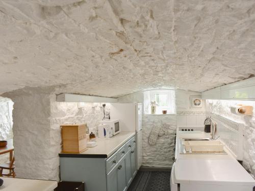 a kitchen with white appliances and a stone wall at Curlew Cottage in Stanhope