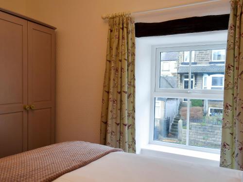 a bedroom with a bed and a window at Parsley Cottage in Tideswell