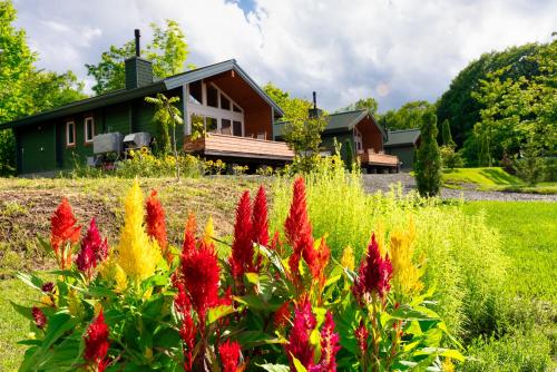 a house with red and yellow flowers in front of it at Chill Village in Biei