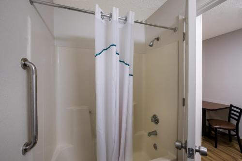 a shower with a white shower curtain in a bathroom at HomeTowne Studios by Red Roof Covington, GA in Covington
