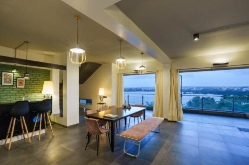 uma sala de estar com uma mesa e cadeiras e uma grande janela em Grey Stone - Lakefront PentHouse Family Rooms em Kolhapur