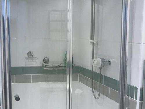 a shower with a glass door in a bathroom at Driftwood in Aberdyfi