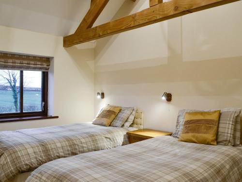 2 Betten in einem Zimmer mit Fenster in der Unterkunft Little Meadow in Dearham