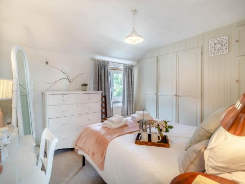 - une chambre blanche avec un lit et une commode dans l'établissement Heartwarming Cottage, à Wickham Market