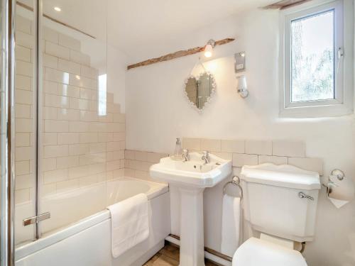 La salle de bains blanche est pourvue d'une baignoire, de toilettes et d'un lavabo. dans l'établissement Heartwarming Cottage, à Wickham Market