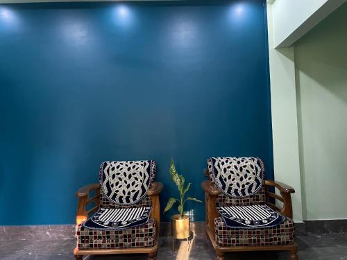 dos sillas de mimbre sentadas junto a una pared azul en Deka’s Homestay en Tezpur