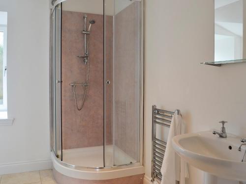 een douche met een glazen deur naast een wastafel bij Kirroughtree Steading 1 - Uk5859 in Newton Stewart