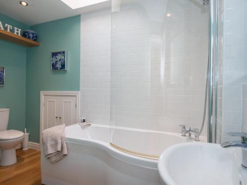 a bathroom with a tub and a toilet and a sink at Cottage On The Green in Calne