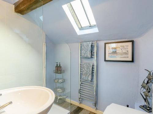uma casa de banho com um lavatório branco e uma clarabóia em The Smithy - E5445 em Brassington