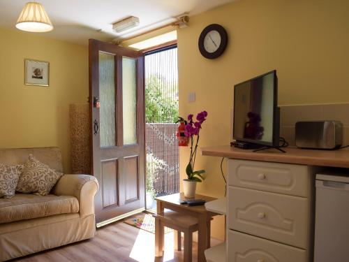 a living room with a couch and a tv at The Byre in Lympsham