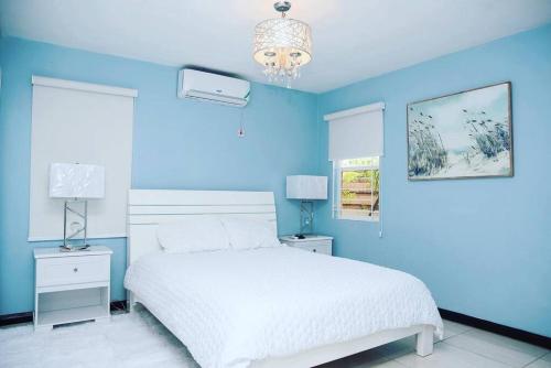 a blue bedroom with a white bed and a blue wall at Breathtaking Oceanfront in Portmore