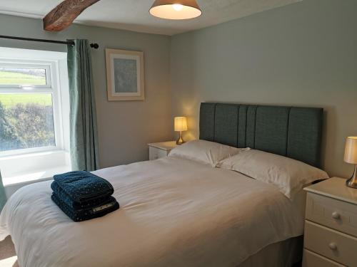 a bedroom with a bed with a suitcase on it at Hillside Farm Cottage in Grange Over Sands