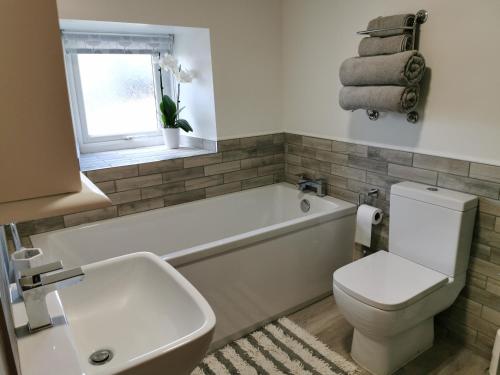 a bathroom with a tub and a toilet and a sink at Hillside Farm Cottage in Grange Over Sands