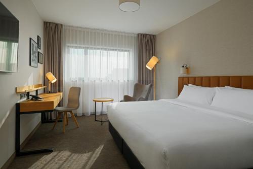 a hotel room with a bed and a desk and a bed and a bed at Four Points by Sheraton Warsaw Mokotow in Warsaw