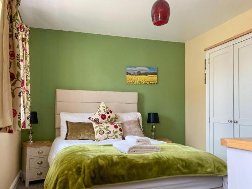 a green bedroom with a bed with green walls at Cosy Cotswolds Townhouse in Honington