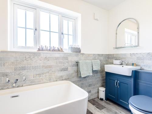 a bathroom with a tub and a sink and a toilet at Lilium Cottage in North Somercotes