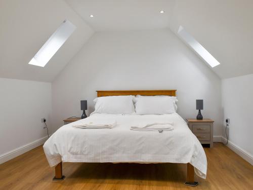 a white bedroom with a large bed with white sheets at Fallow Cottage - Uk33488 in Hadleigh