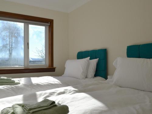 a bedroom with two white beds and a window at Wester Links in Fortrose