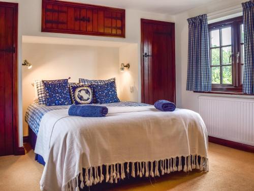 a bedroom with a bed with blue pillows at Honeysuckle Cottage in Mickleton