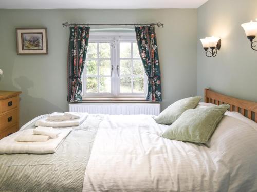 a bedroom with a large bed and a window at Well Cottage in Itchingfield