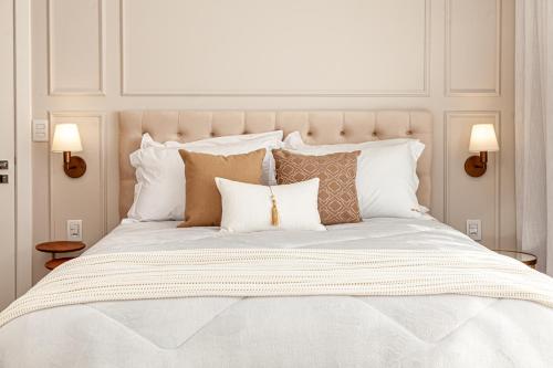 a large white bed with pillows on it with two lamps at Villa Toscana - Vale dos Vinhedos in Bento Gonçalves