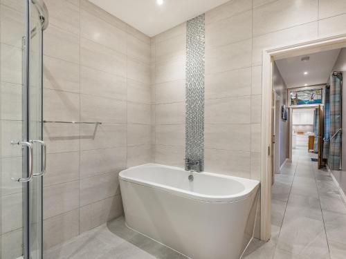 a white bath tub in a bathroom with a shower at Primrose Cottage in Holyhead