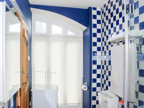 uma casa de banho com WC e azulejos azuis e brancos em The Byre em West Stour