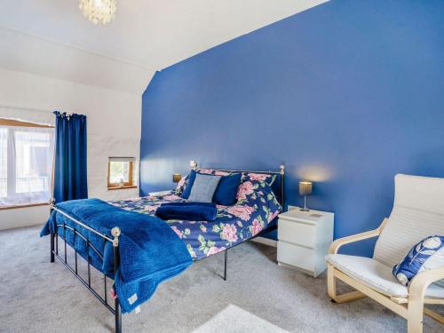 a blue bedroom with a bed and a chair at Y Buedy - Uk40699 in Lampeter