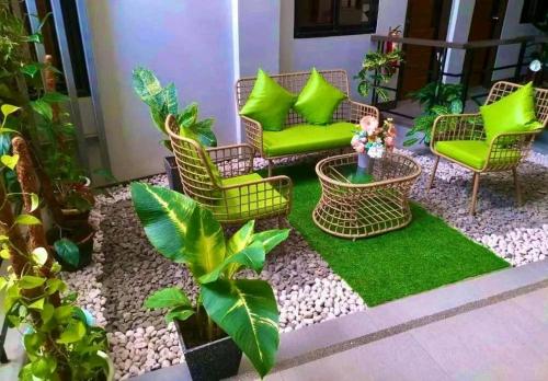 un patio con sillas verdes, plantas y césped en Dachannry's Place Hotel en Cagayán de Oro