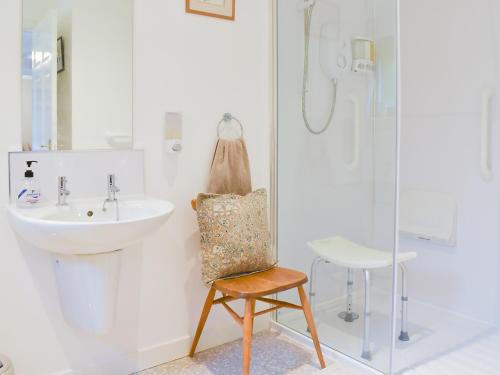 a bathroom with a sink and a chair next to a shower at Drummond Neuk in Brackley