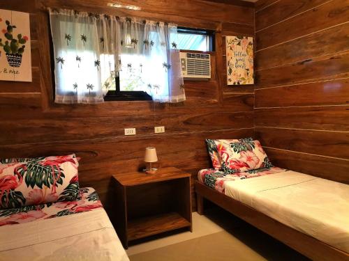 a room with wooden walls and two beds and a window at LADY GHAGHA ROOM RENTALs in San Vicente